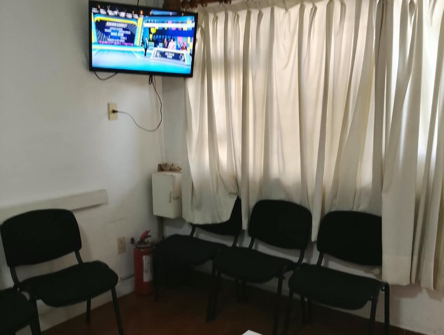 Sala de espera del consultorio, con sillas, televisión y mesa
